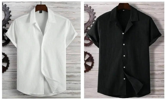 White and black short-sleeve shirts on hangers against a wooden background.