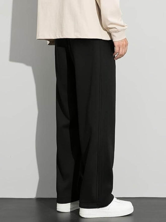 Person wearing black pants and a beige top against a gray background