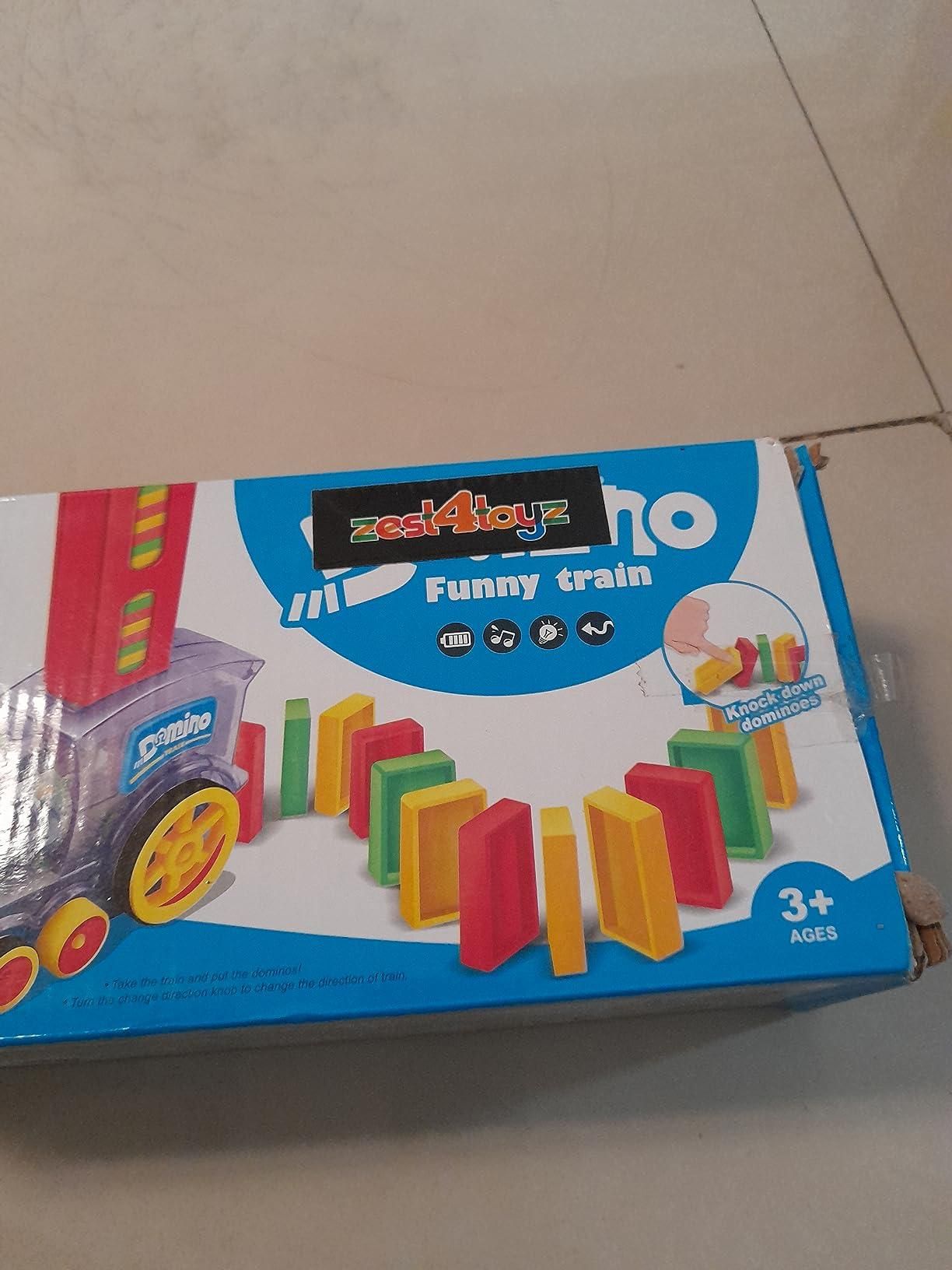 Box of a toy train set with colorful blocks and wheels on a light gray floor.