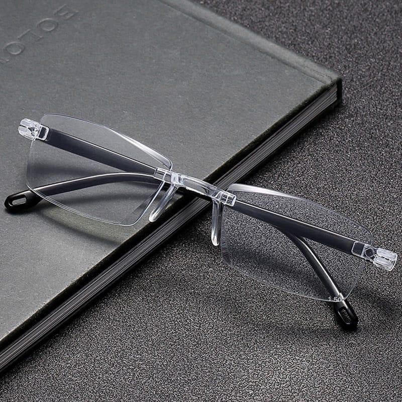 Clear rimless eyeglasses on a black surface with a notebook