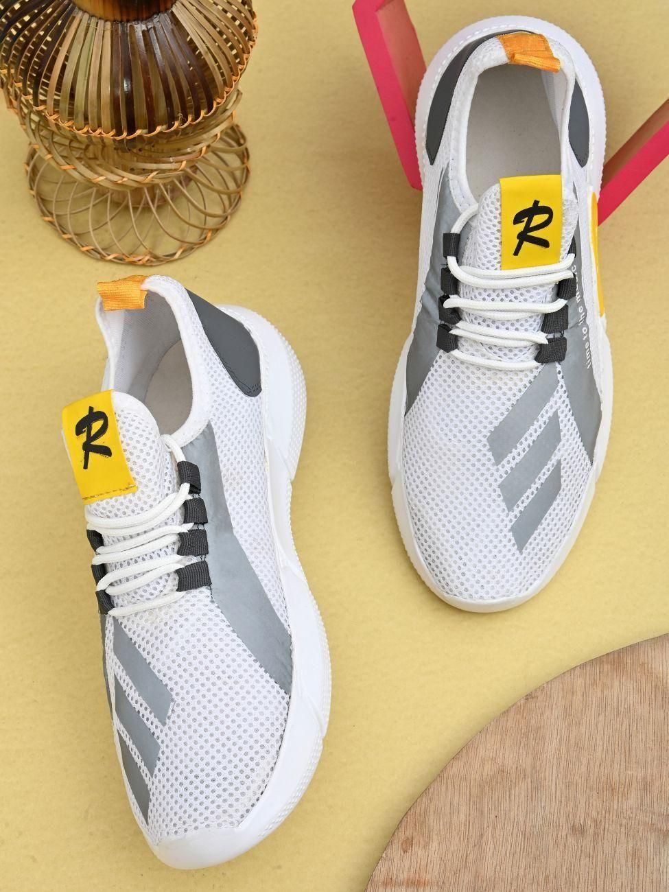 White and gray athletic shoes with yellow accents on a yellow surface