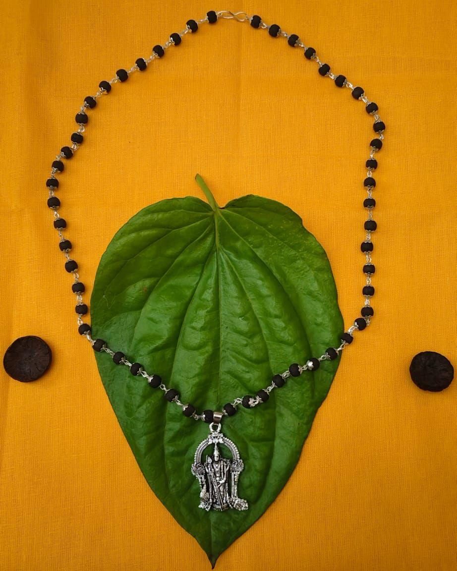 Karungali Mala with Murugan Locket on a green leaf, showcasing traditional black beads and spiritual design.