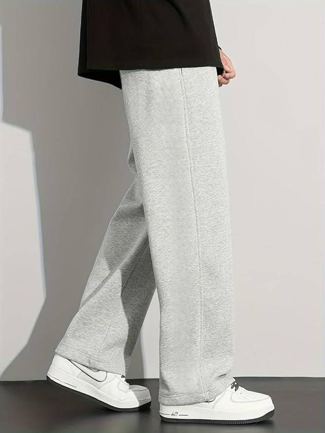 Person wearing gray sweatpants and white sneakers on a plain background