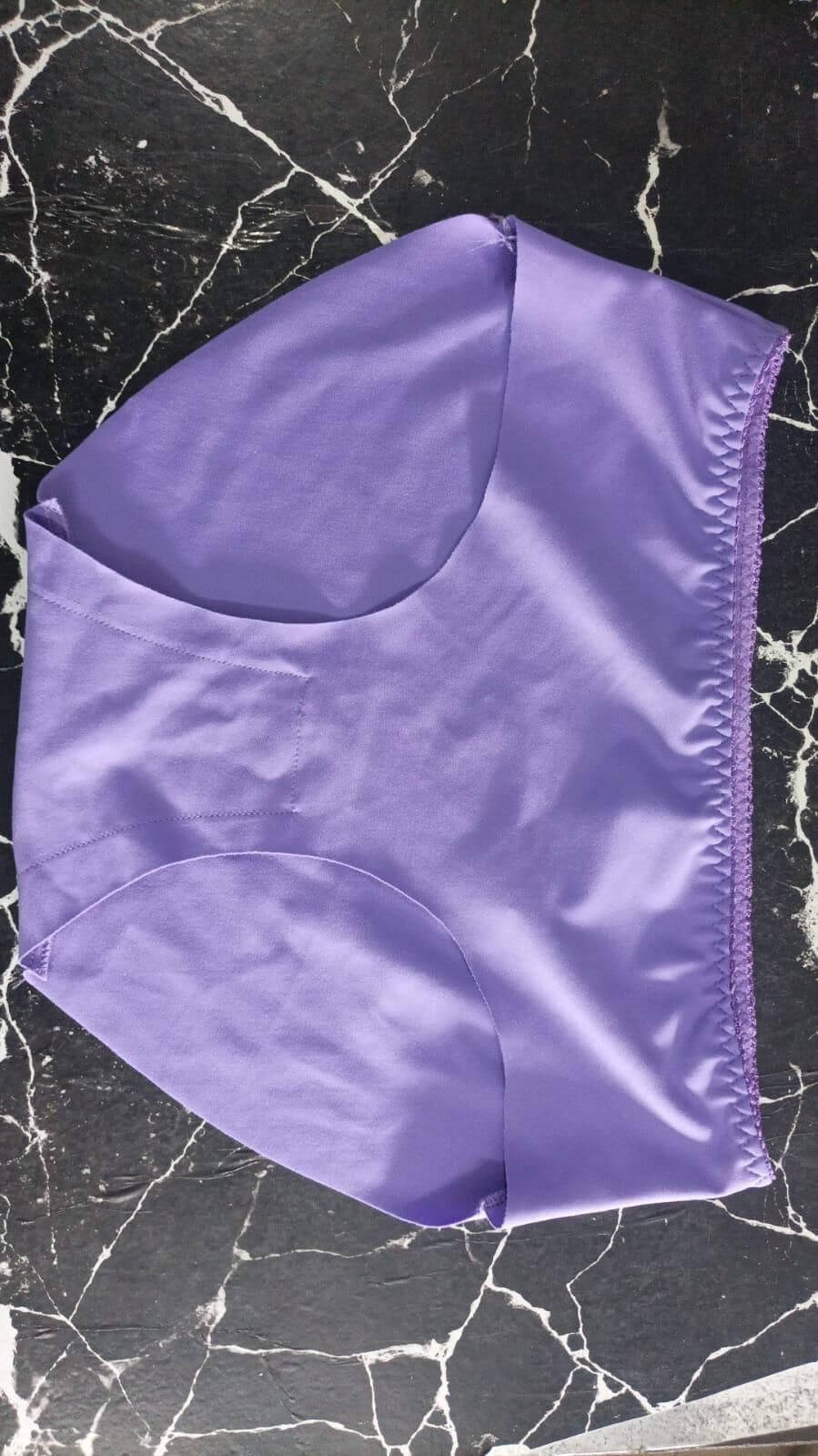 Women's Seamless Underwear Purple fabric square on a black marble surface