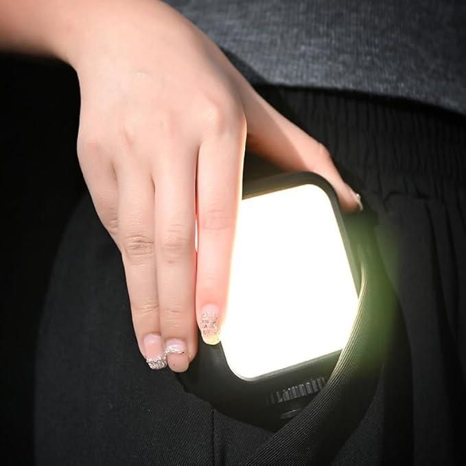 Hand holding a video light source with a dark background