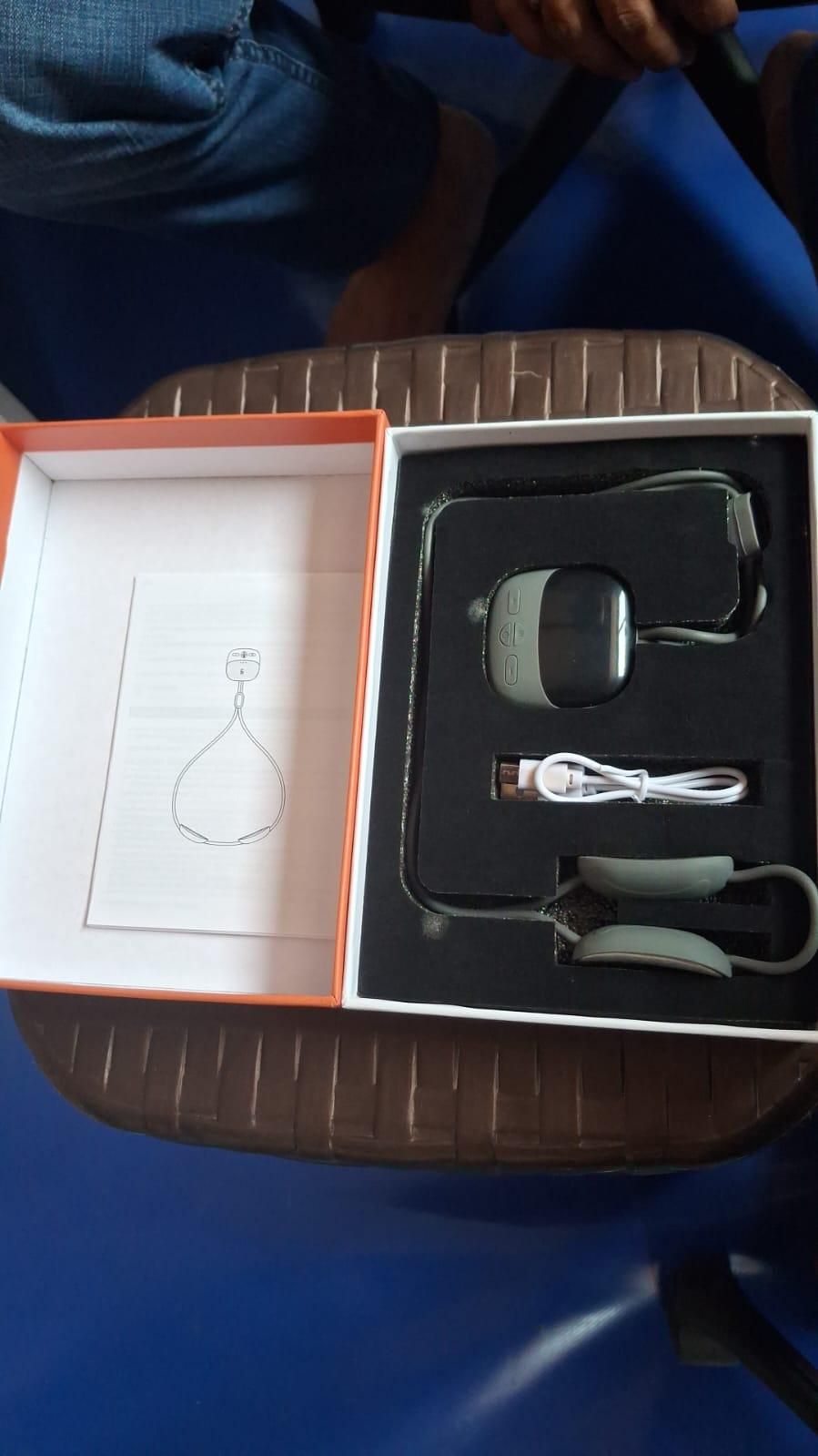Complete box contents of neck massager including remote, wires, and manual