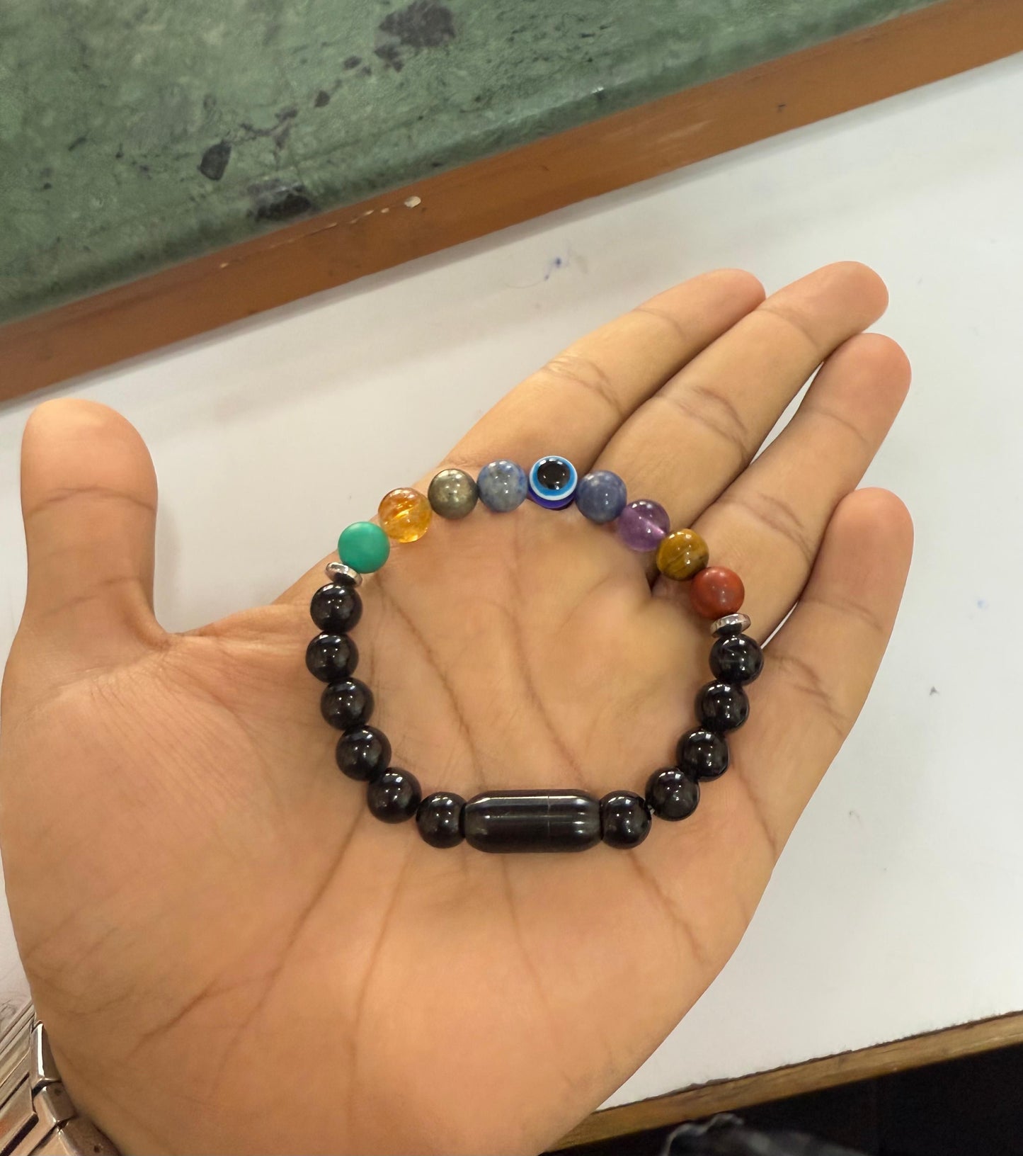 Hand holding aSuper 9 Chakra Healing Bracelet on a white surface