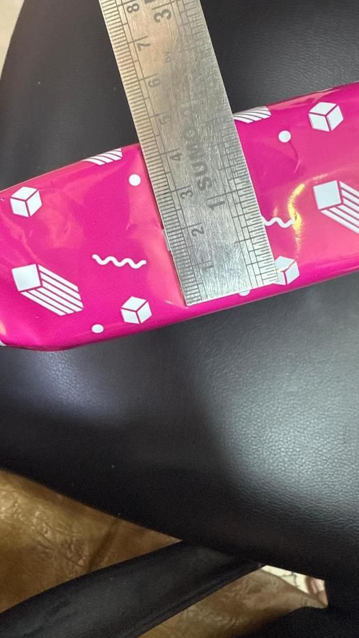 Pink packaging with a ruler for scale on a dark surface